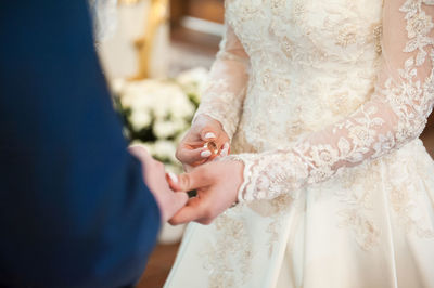 Close-up of woman holding groom hands and wearing ring during wedding ceremony