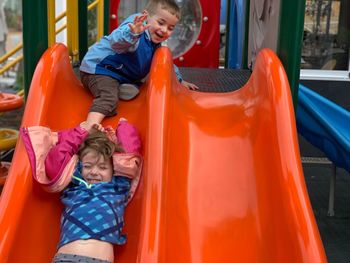 Happy siblings playing on slide at playground