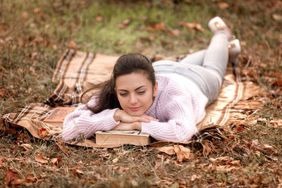 Woman with book lying at park during autumn