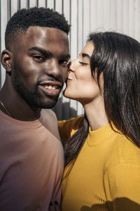 Man kissing woman against wall