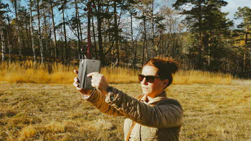 Woman photographing against trees