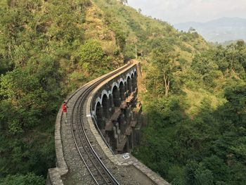 High angle view of man standing by mountain on railway bridge