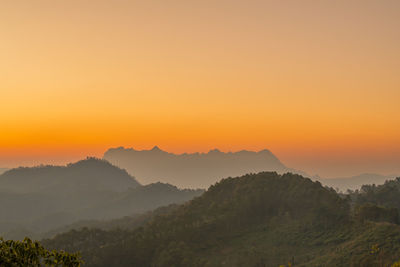 Scenic view of mountains against orange sky