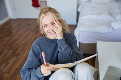 Young woman using digital tablet while sitting on table