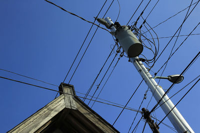 Low angle view of electricity pylon against clear blue sky