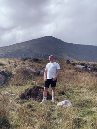 Rear view of man standing on mountain against sky