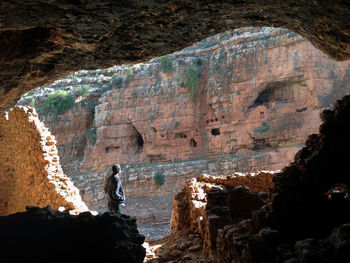 Rear view of man standing by rock formation