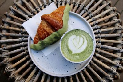 High angle view of matcha tea with croissant food on table