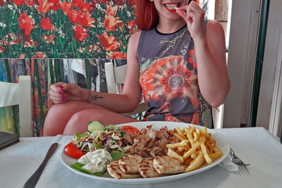 Midsection of woman eating food while sitting at table