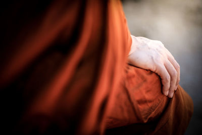 Midsection of monk sitting on seat