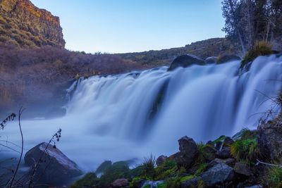 Scenic view of waterfall against sky