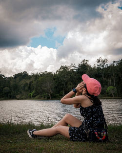 Woman wearing hat against trees against sky