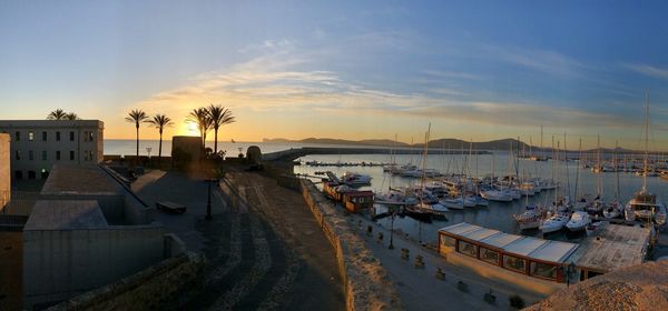 Panoramic view of boats moored at harbor during sunset