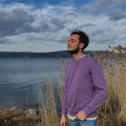 Portrait of young man standing against lake