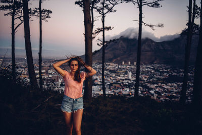 Full length of young woman standing against sky during sunset