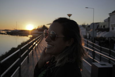 Smiling woman in sunglasses at harbor against sky