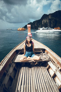 Woman sitting in boat on sea against sky