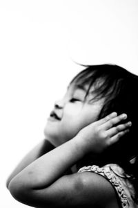 Close-up of girl with hands covering ears on white background