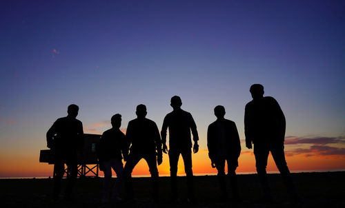 Rear view of silhouette people standing against sky during sunset