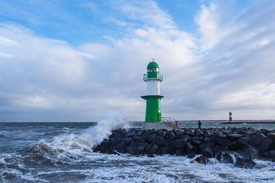 Lighthouse by sea against sky