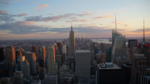 Modern buildings in city against sky during sunset