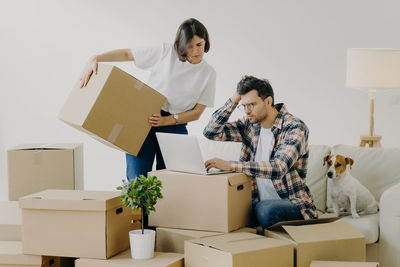 Couple using laptop on boxes at new house