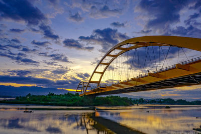 Low angle view of bridge against cloudy sky during sunset