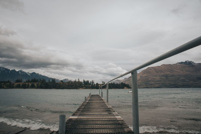 Wooden jetty leading to lake with mountain view.