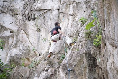 Low angle rear view of man climbing on rock