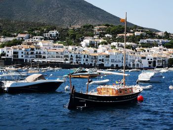 Sailboats moored in harbor by buildings in city