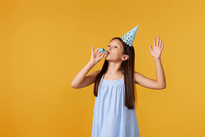 Young woman drinking juice against yellow background