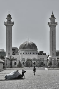 People in front of historical building against clear sky