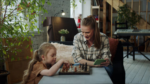 Mother and daughter playing chess at home