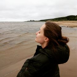 Side view of woman with eyes closed standing on shore