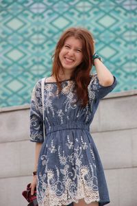 Portrait of smiling woman standing against wall