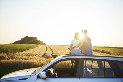 Rear view of man driving car on field against clear sky