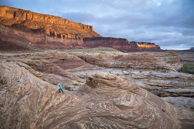 Woman hiking in a dramatic desert landscape at sunrise.