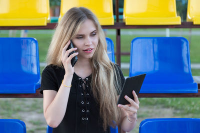 Young woman talking through mobile phone while sitting on chair