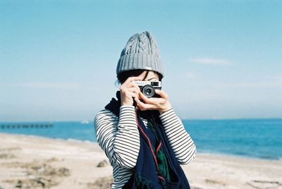 Man photographing at beach against sky