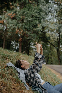 Side view of woman taking selfie lying down outdoors