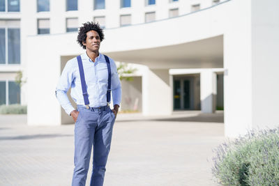 Portrait of young man standing against building