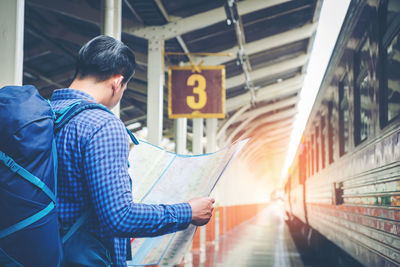 Man reading map while standing at railroad station platform