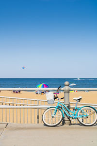 Bicycles on beach against clear blue sky