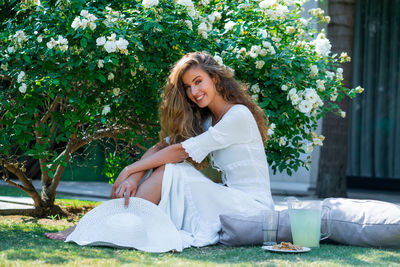 Portrait of smiling young woman against white plants