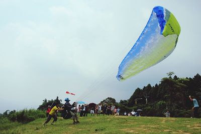 People on grassy field against sky