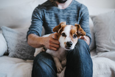 Midsection of man with dog sitting on sofa