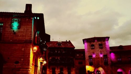 Low angle view of illuminated building against cloudy sky