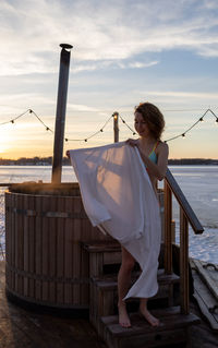 Rear view of young woman standing against sea