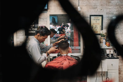 Rear view of people standing in mirror