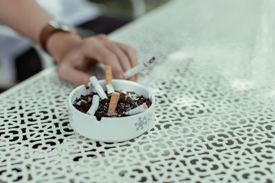 Midsection of person holding cigarette on table